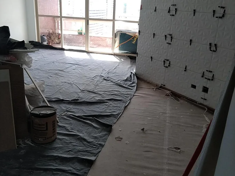 Sala em obra com painel ripado em montagem e lona protetora